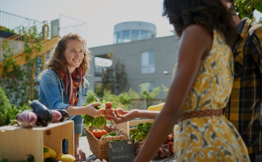 Woman purchasing beets from a local vendor at a farmers market.